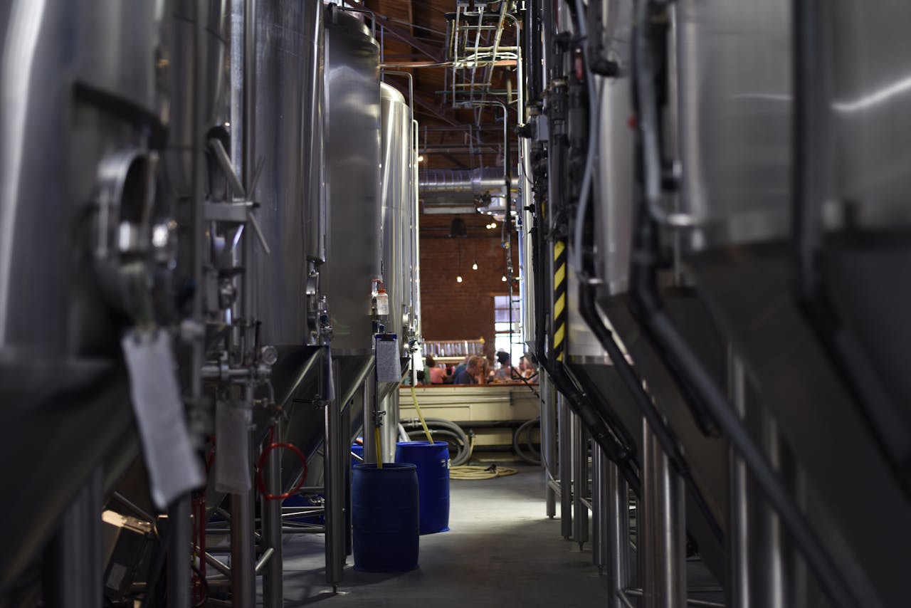 Services Inside view of a modern brewery with large stainless steel tanks and machinery for beer production.