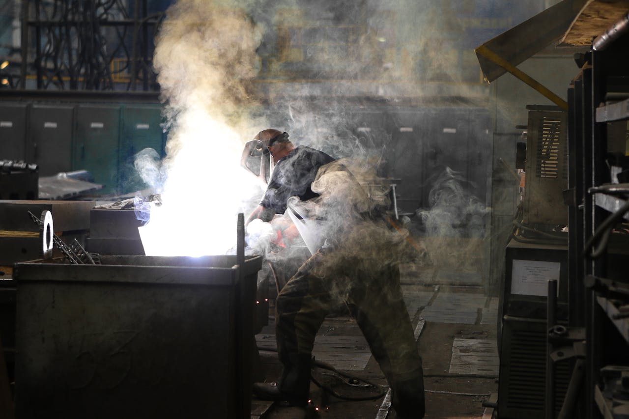 Services A skilled welder working with intense sparks and smoke in an industrial workshop, showcasing safety and precision.